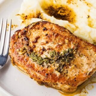 Golden seared pork chops with melted butter and herbs