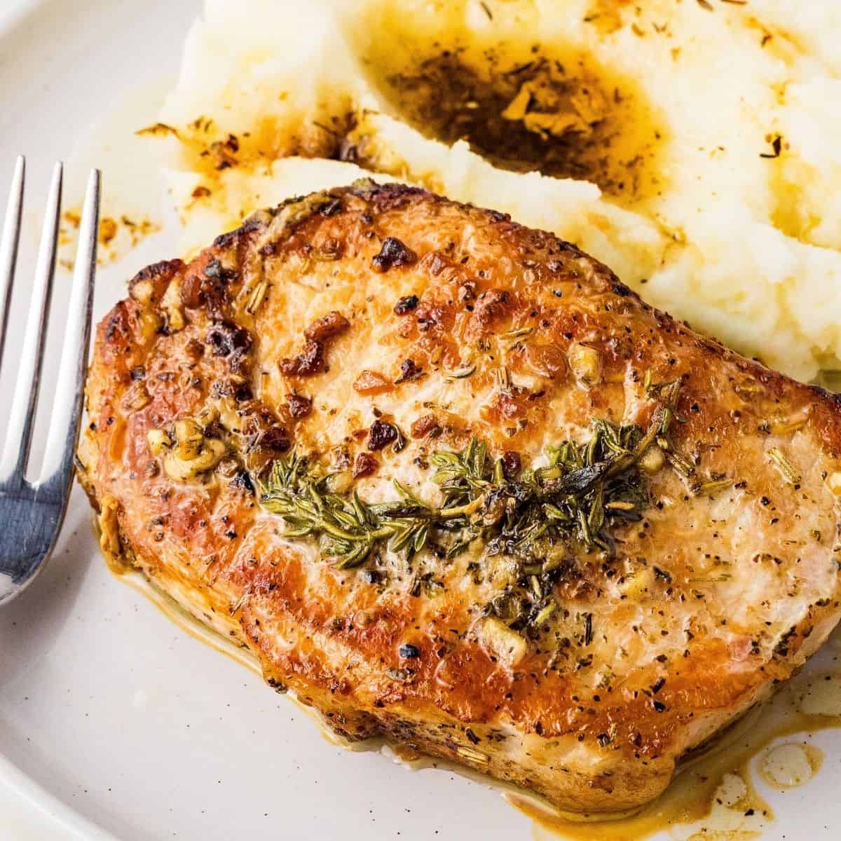 Golden seared pork chops with melted butter and herbs
