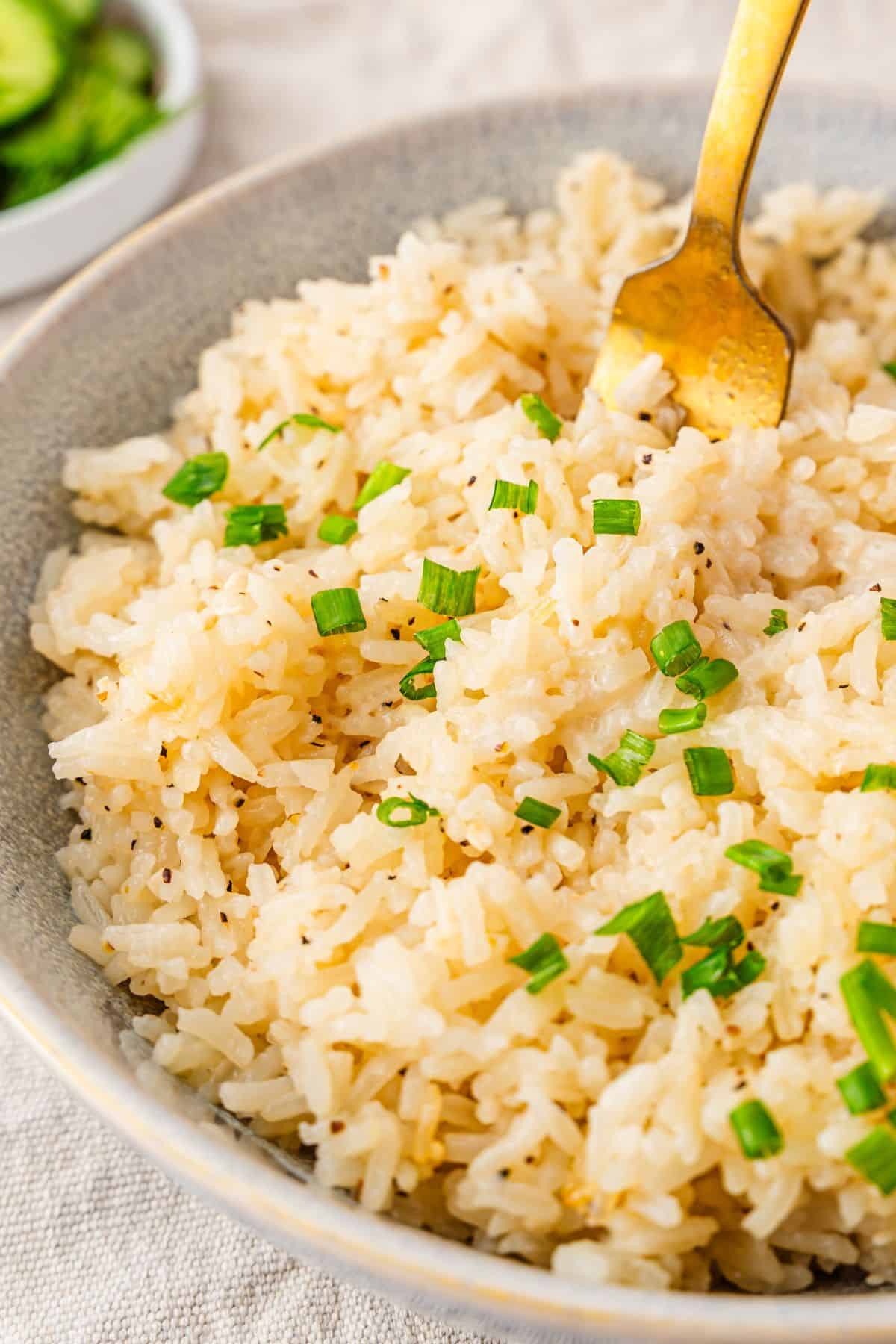 garlic butter jasmine rice in a blue bowl with a gold fork