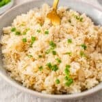 a bowl of garlic butter rice with chopped chives on top