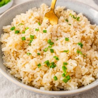 a bowl of garlic butter rice with chopped chives on top