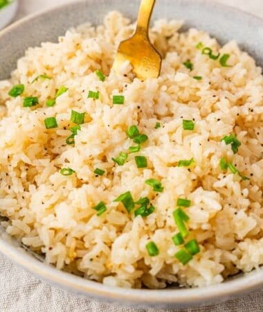 a bowl of garlic butter rice with chopped chives on top