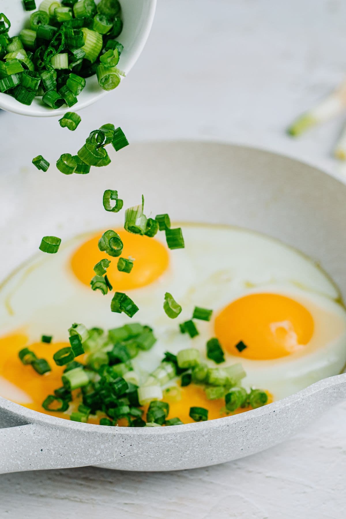 adding oil, eggs, and green onions to a skillet