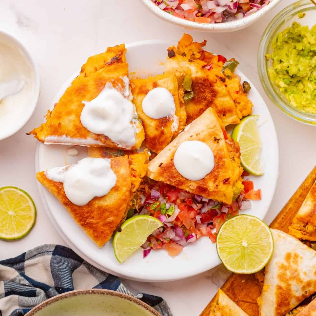 Cheesy shredded chicken quesadilla with saut&eacute;ed peppers on a serving plate
