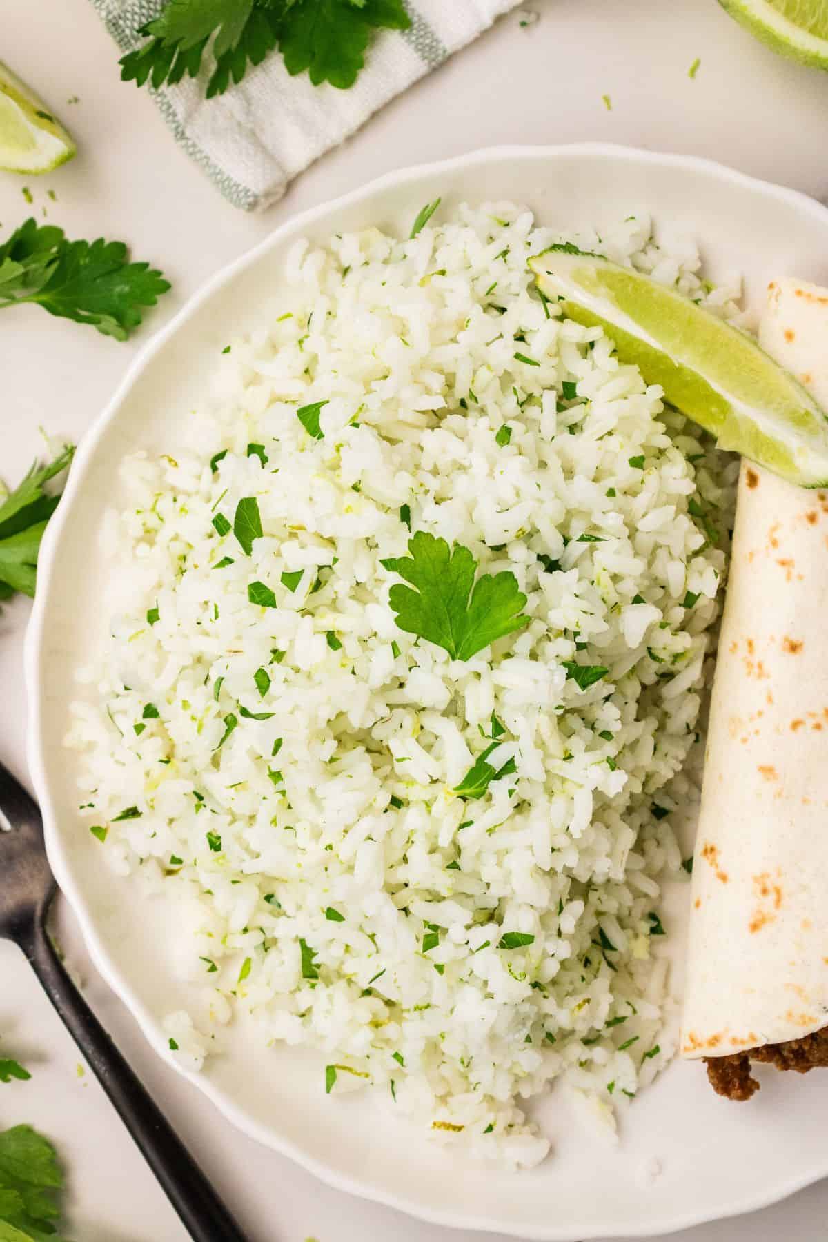 Cilantro and lime rice topped with fresh chopped herbs on a plate with a taco