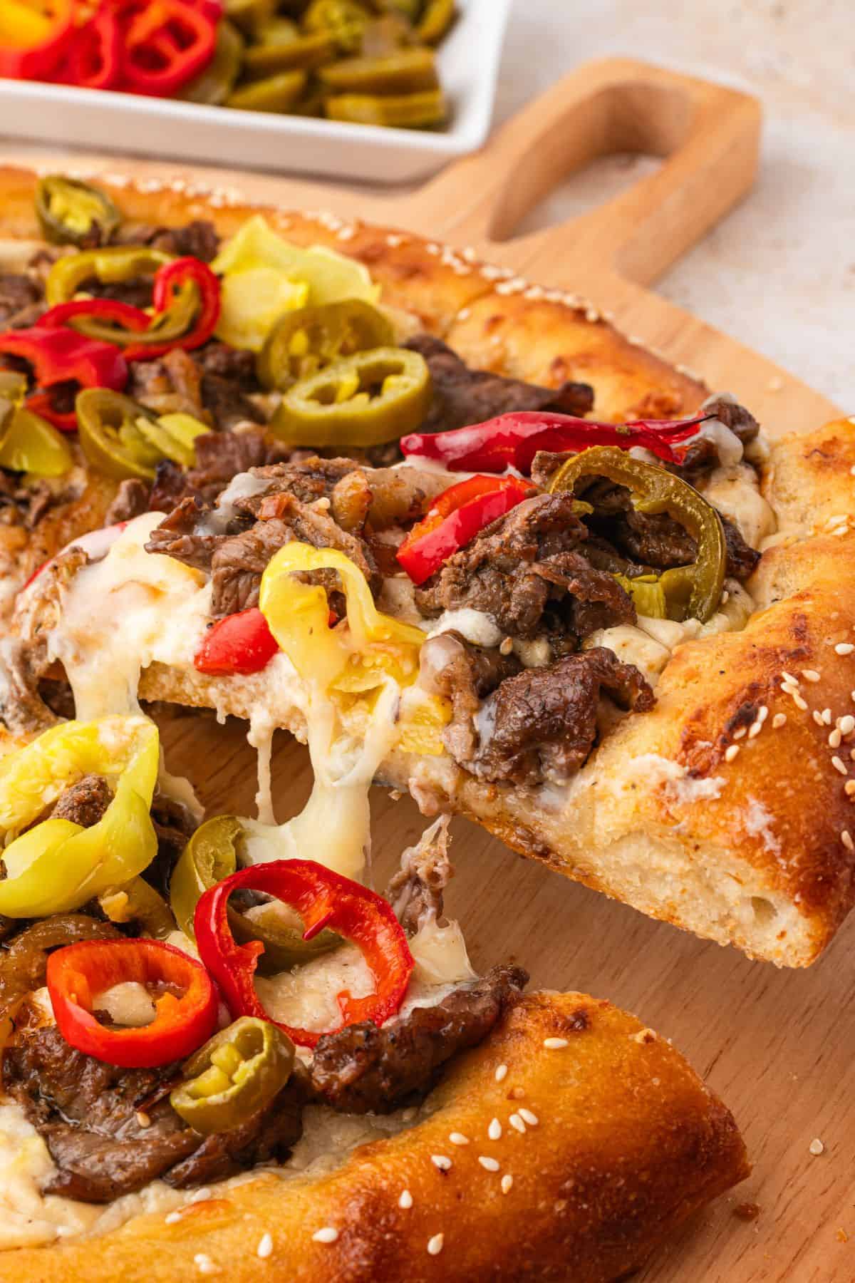 Philly cheese steak pizza sauce spread over crispy crust