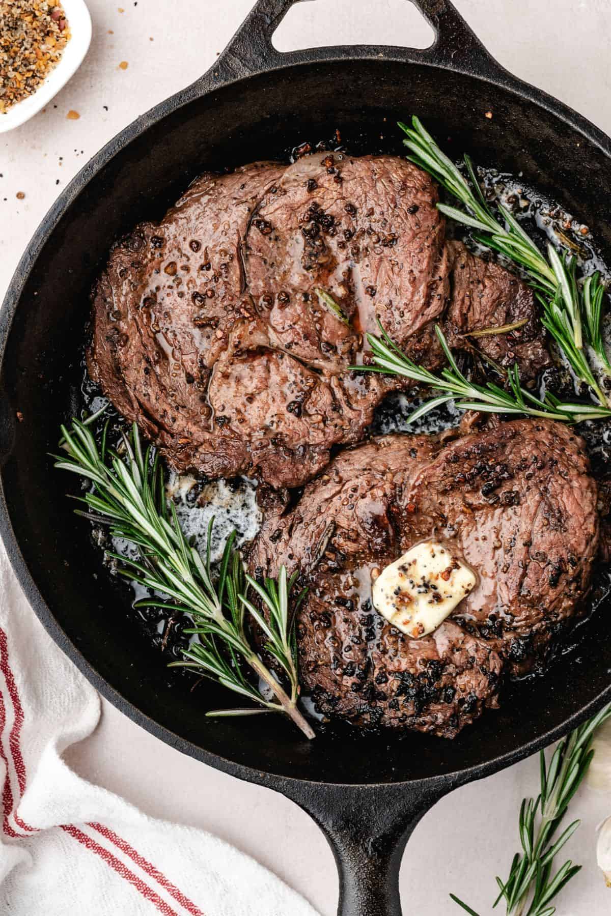 Juicy pan seared steak finished with rosemary butter in a hot skillet