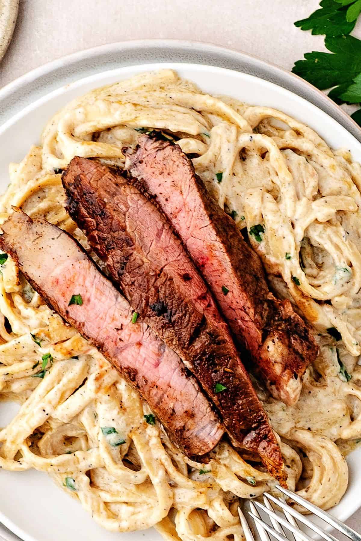 Steak pasta with sliced seared steak over creamy garlic Parmesan sauce