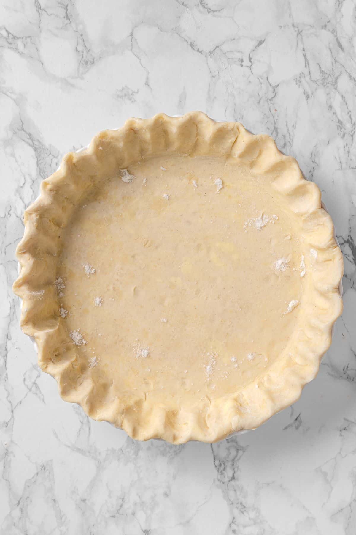 all butter pie crust trimmed and crimped in a pie plate