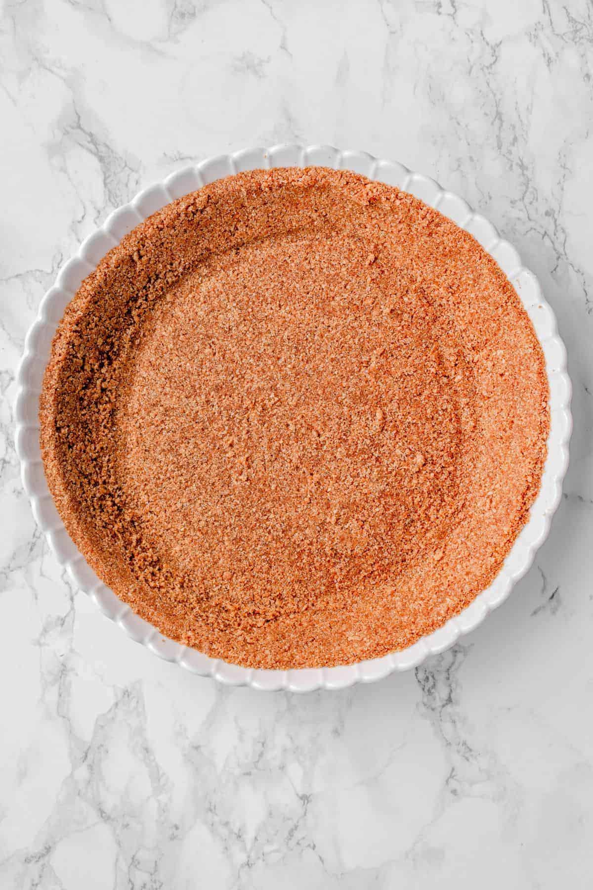 Homemade graham cracker pie crust cooling in a pie plate
