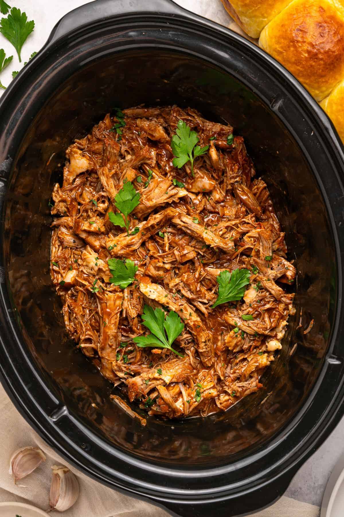 Pulled pork in slow cooker cooked until it easily pulls apart with a fork