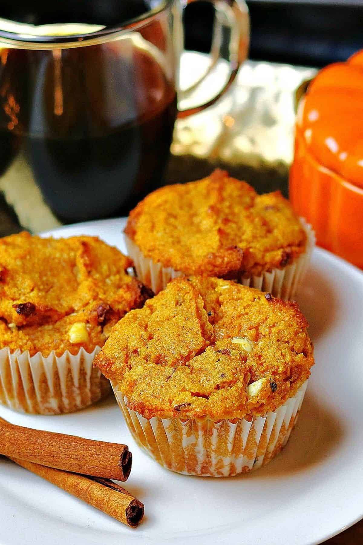 three low carb pumpkin spice muffins on a plate with a cup of coffee