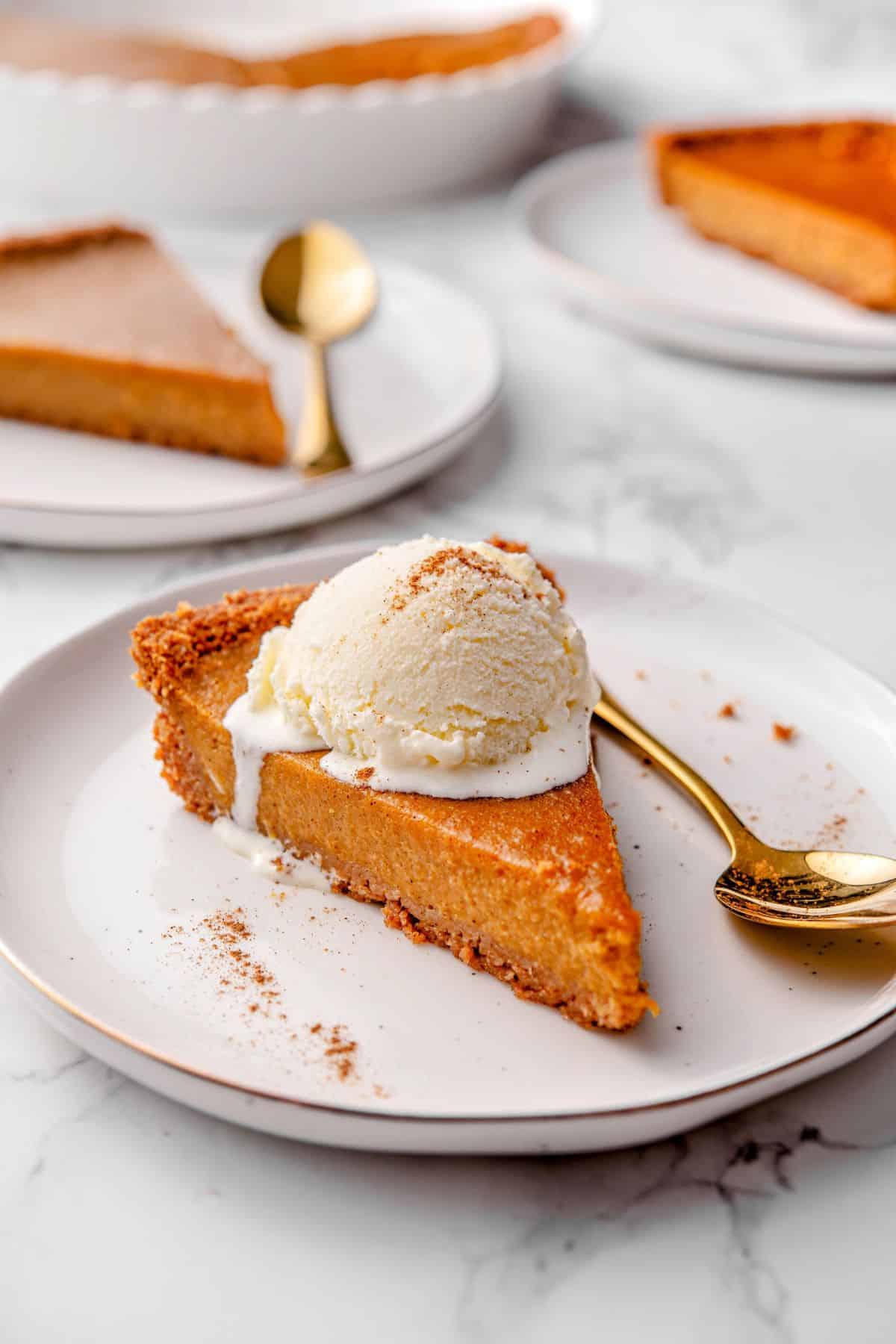 Pumpkin pie and graham cracker crust served with a scoop of vanilla ice cream