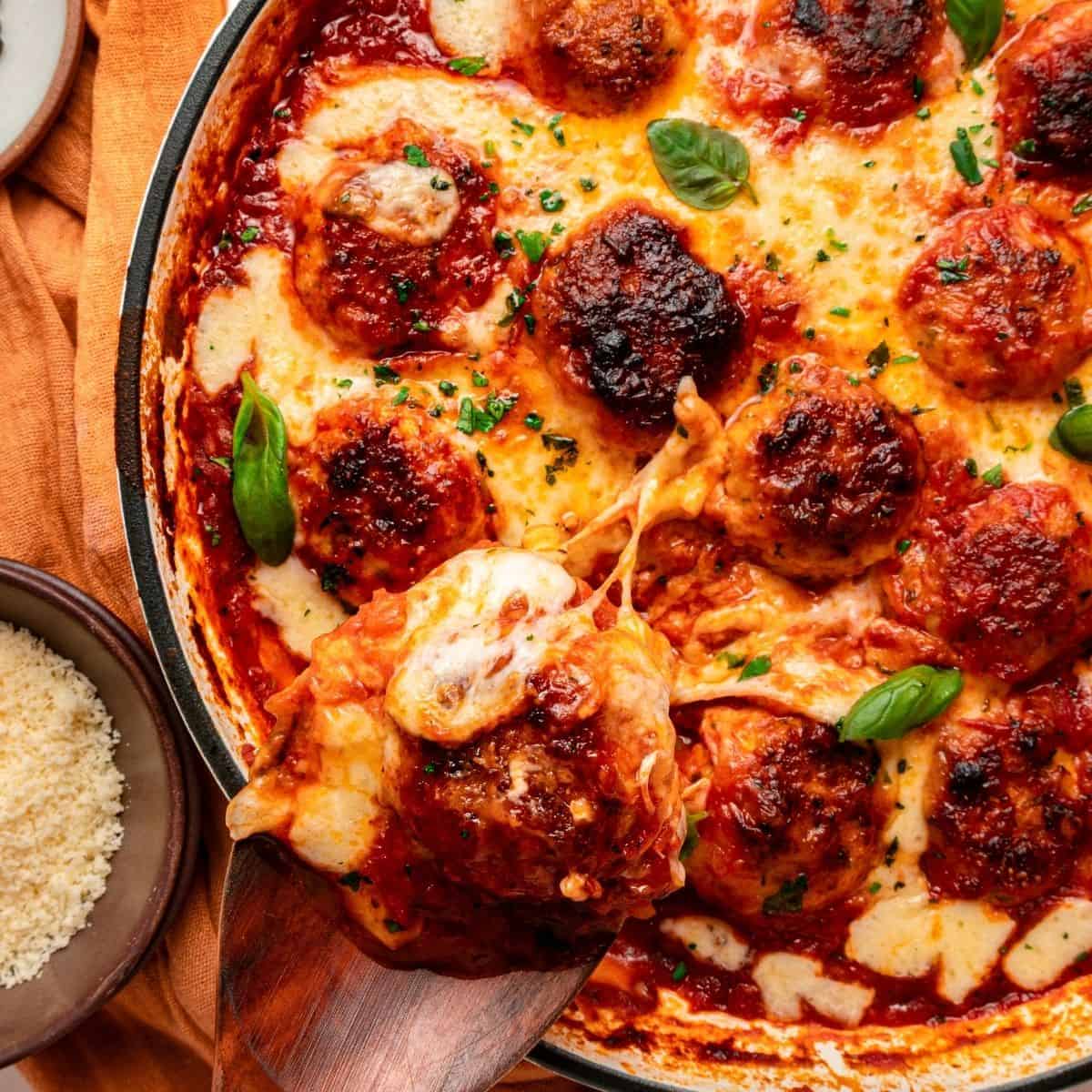 Skillet chicken parm meatballs covered with bubbling mozzarella and Parmesan