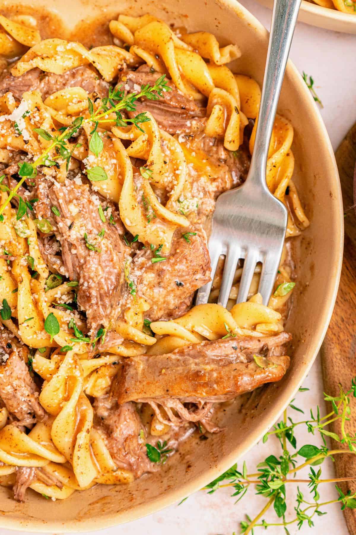Crockpot beef and noodles with egg noodles soaking up savory beef broth