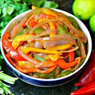 red, yellow, and green bell peppers cooked in a bowl with red onions