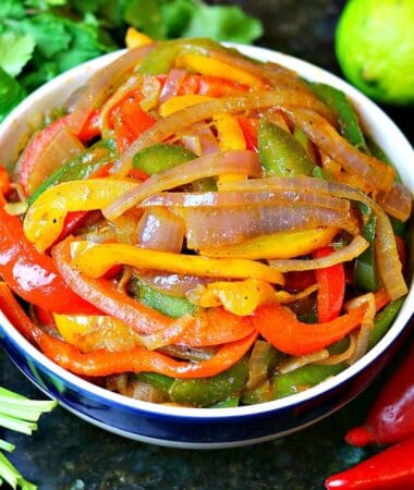 red, yellow, and green bell peppers cooked in a bowl with red onions