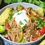 a keto burrito bowl with cauliflower rice, fajita veggies, pork carnitas, sour cream and sliced tomatoes