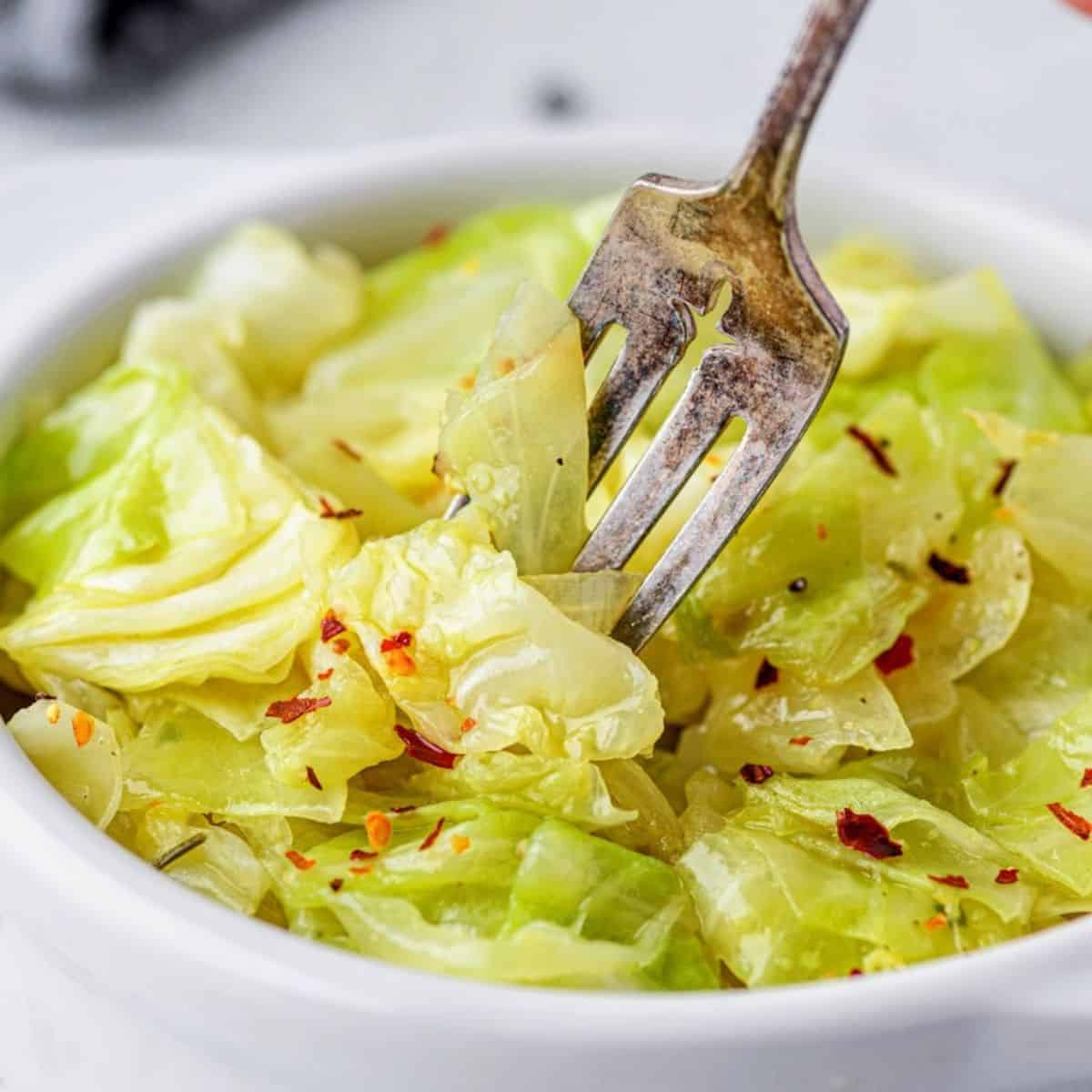 Braised cabbage served in a bowl with soft cabbage leaves and buttery cooking juices
