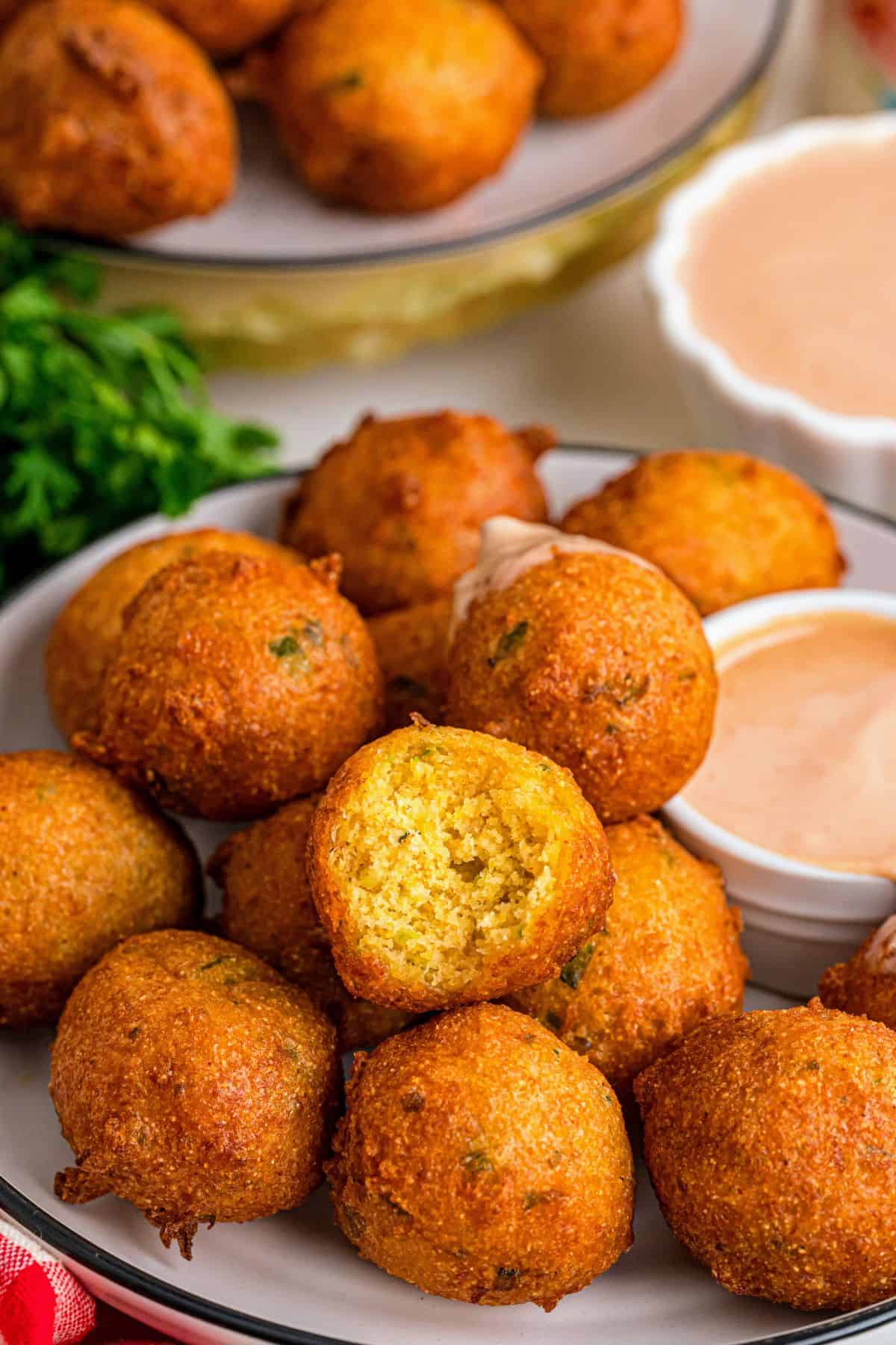 Homemade hush puppies recipe with Cajun seasoning and a bowl of dip on the side