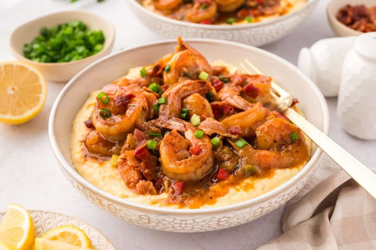 shrimp and grits in a bowl with a brown sauce over top of creamy cheddar grits
