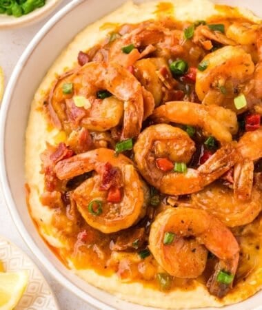 Creamy shrimp and grits topped with Cajun shrimp, crispy bacon pieces, and a rich buttery sauce