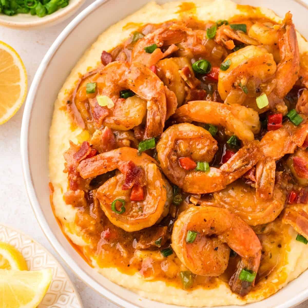 Creamy shrimp and grits topped with Cajun shrimp, crispy bacon pieces, and a rich buttery sauce